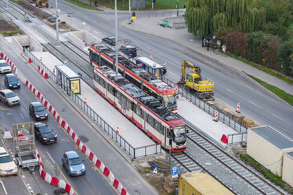 widok ulicy z lotu ptaka, na środku przystanek tramwajowy i dwa stojące na nim tramwaje