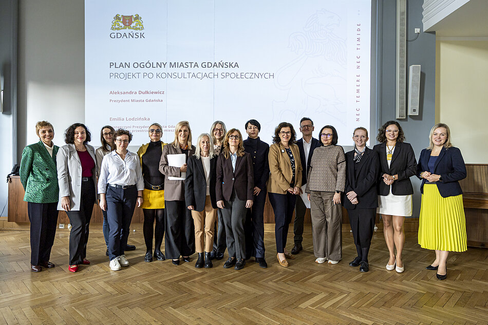 grupa osób na tle ekranu prezentacyjnego z napisem Plan ogólny miasta gdańska. projekt po konsutacjach