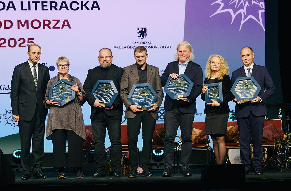 Mężczyźni i kobiety stojący w rzędzie, w ręku trzymają statuetki