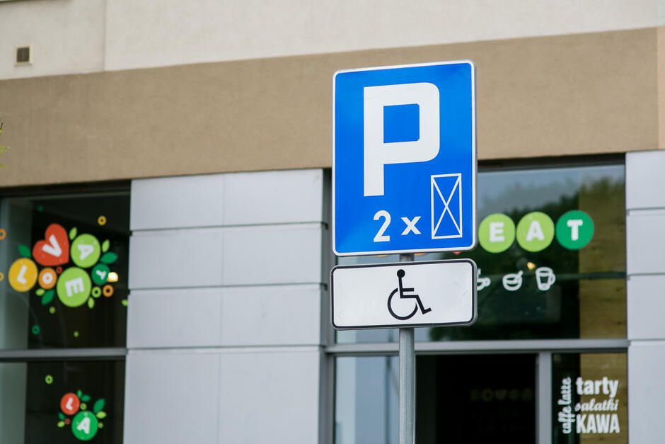 Na zdjęciu widoczny jest znak drogowy parkingu przeznaczonego dla osób z niepełnosprawnościami