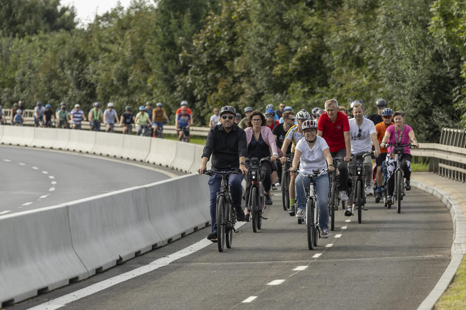 Rowerzyści jadący nową drogą rowerową w al. Armii Krajowej w słoneczny dzień
