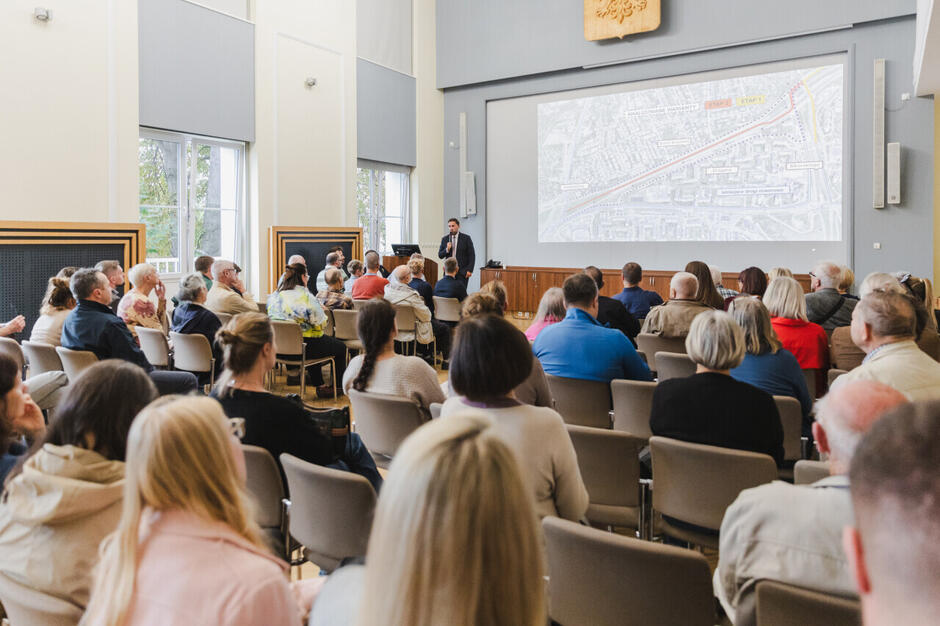 Uczestnicy spotkania nt. II etapu ekostrady wzdłuż al. Armii Krajowej w Gdańsku, zgromadzeni w Urzędzie Miejskim w Gdańsku. Na ścianie wyświetlana jest prezentacja poświęcona planowanej inwestycji