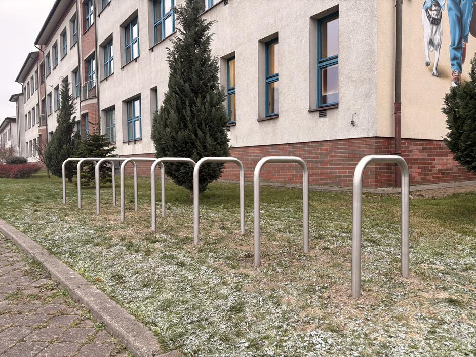 Osiem stojaków rowerowych zamontowanych na trawniku, z których korzystać mogą osoby odwiedzające SP nr 85 na Jasieniu