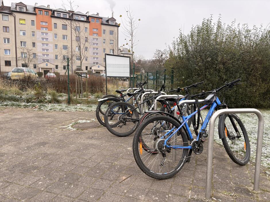 Parking rowerowy w otoczeniu krzewów oraz osiedla mieszkaniowego, na terenie Szkoły Podstawowej nr 85