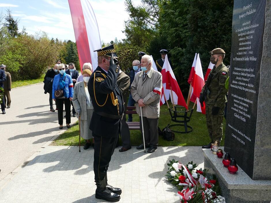 strażnik oddaje hołd pod pomnikiem Ofiar Ponar zaproszeni goście flagi Polski kwiaty.JPG