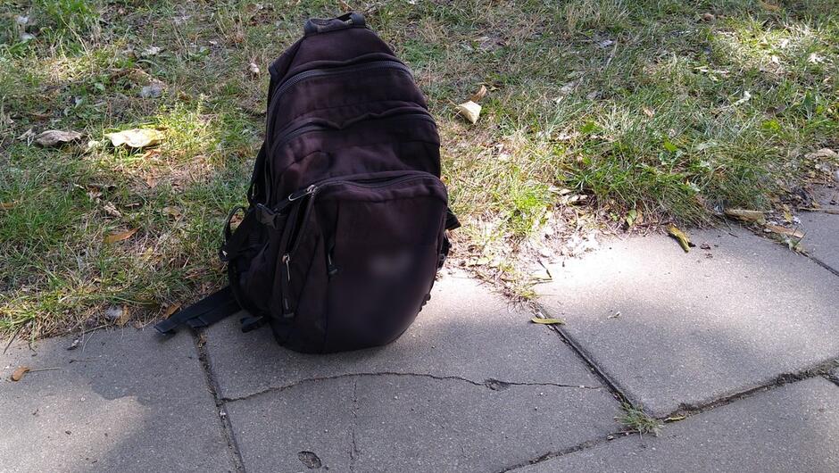 Czarny plecak chodnik trawnik