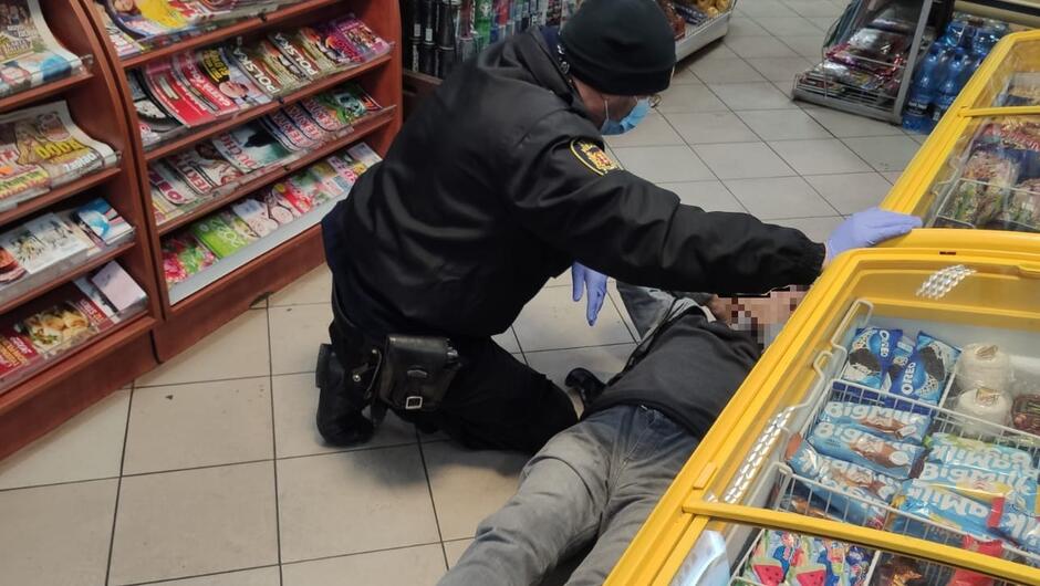strażnik udziela w sklepie pomocy choremu mężczyźnie