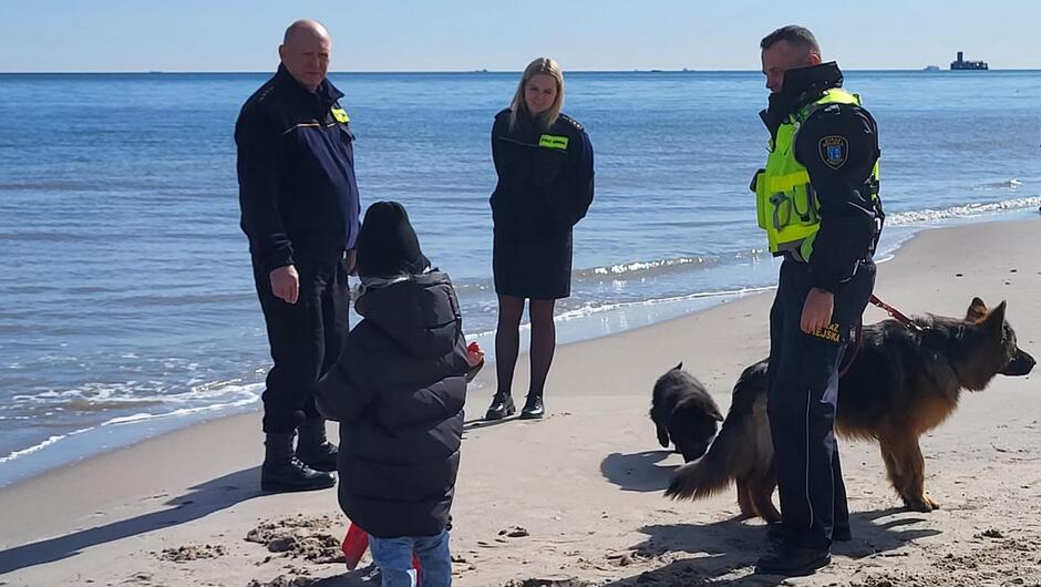strażnicy z psem rozmawiają na plaży z dzieckiem
