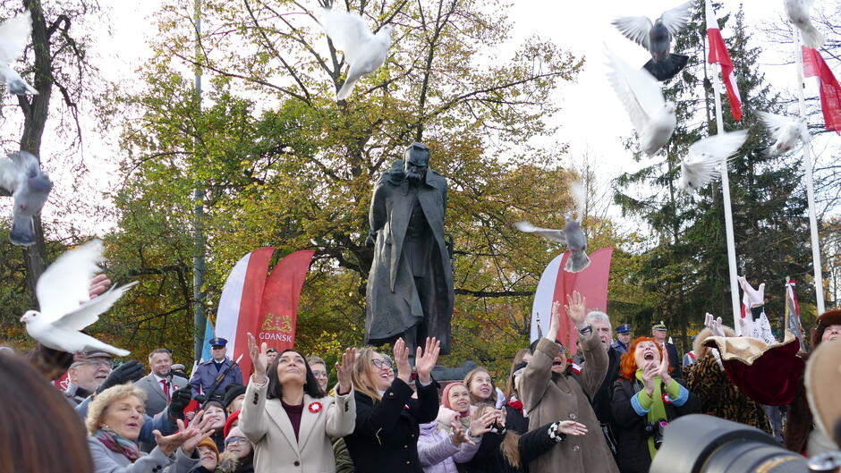 przed pomnikiem uczestnicy wypuszczaja golebie