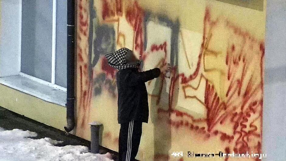 Mężczyzna maluje graffiti na ścianie budynku