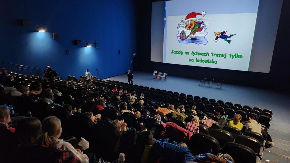 sala kinowa z dziećmi na widowni. Na ekranie wyświetlana prezentacja o bezpiecznych feriach