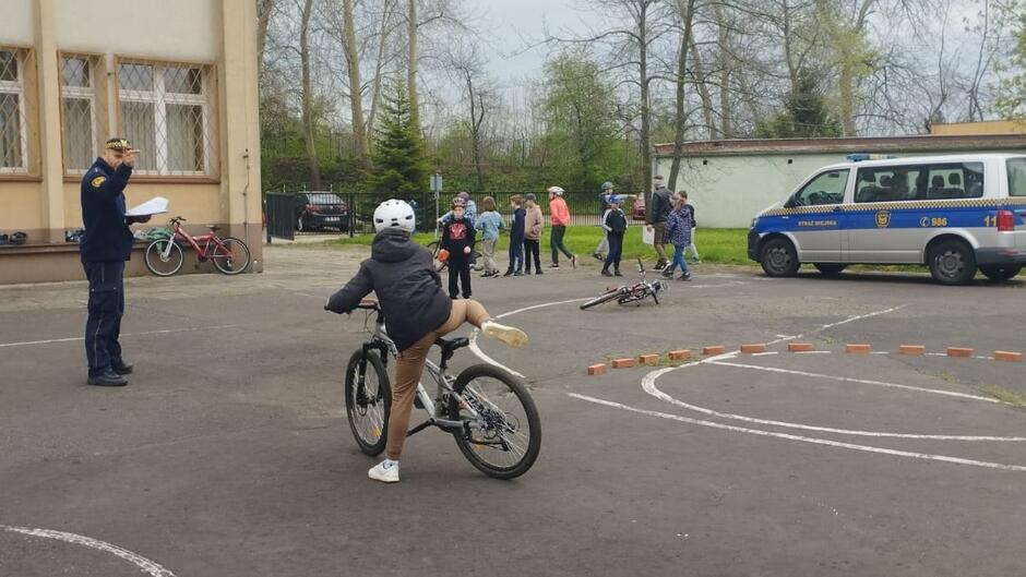 strażnik egzaminuje ucznia w miasteczku rowerowym