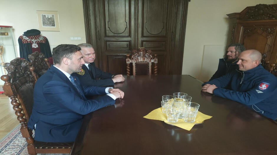 Przy stoliku siedzą Zastępca Prezydenta Gdańska, Komendant Straży Miejskiej oraz dwójka strażników z Wilna. 
