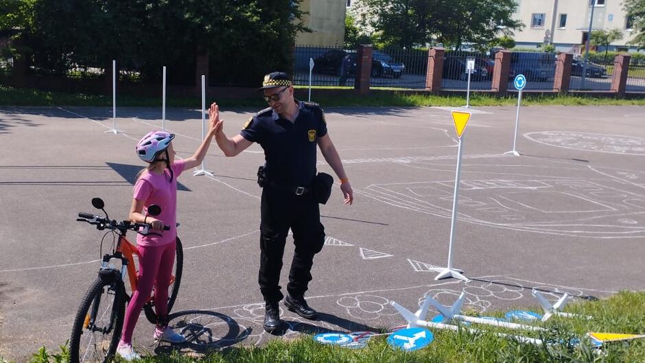 strażnik przybija piątkę z dziewczynką na rowerze