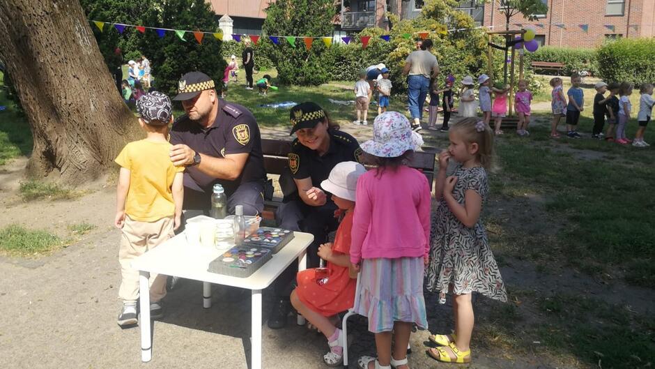 straznicy malują twarze dzieci podczas festynu