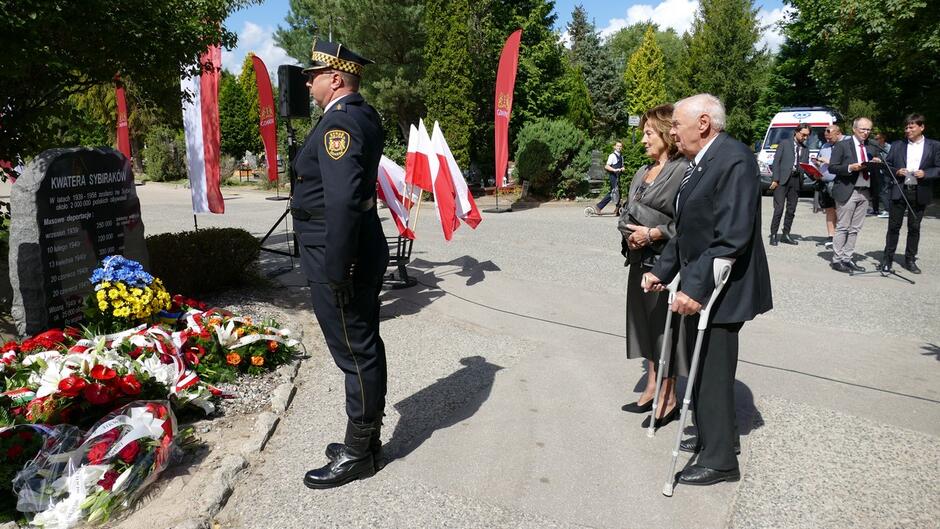 Strażnik salutuje przed pomnikiem. Za nim osoby, w imieniu których złożył kwiaty.