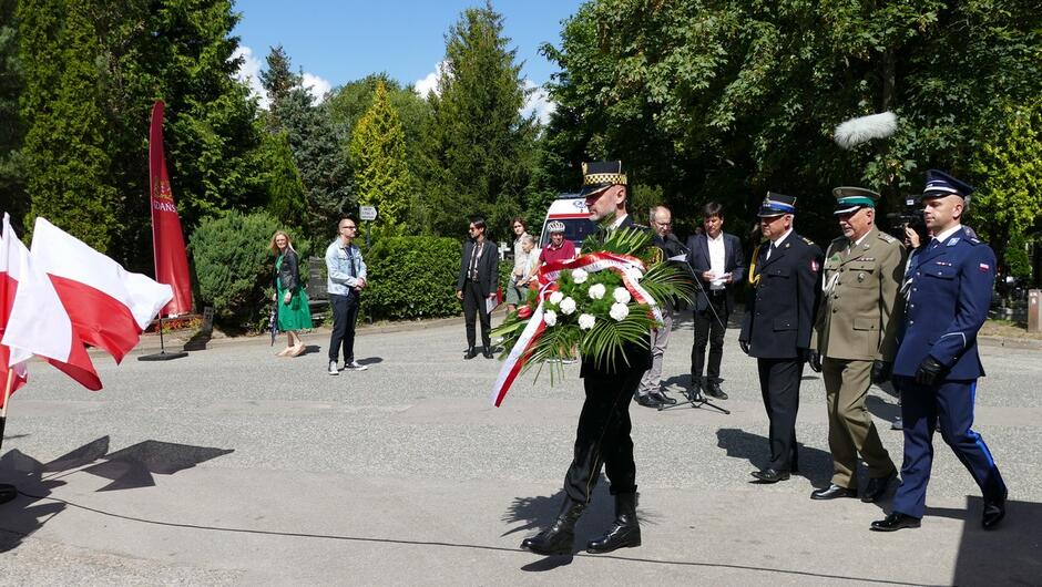 Strażnik miejski składa kwiaty w imieniu przedstawicieli służb mundurowych. 