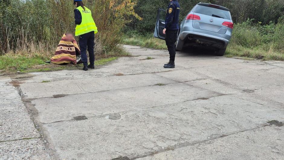 zarośla samochód w rowie melioracyjnym, policjantka strażniczka mężczyzna zawinięty w koc