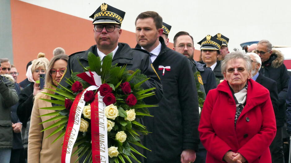 strażnik w wieńcem za nim uczestnicy i inni straznicy