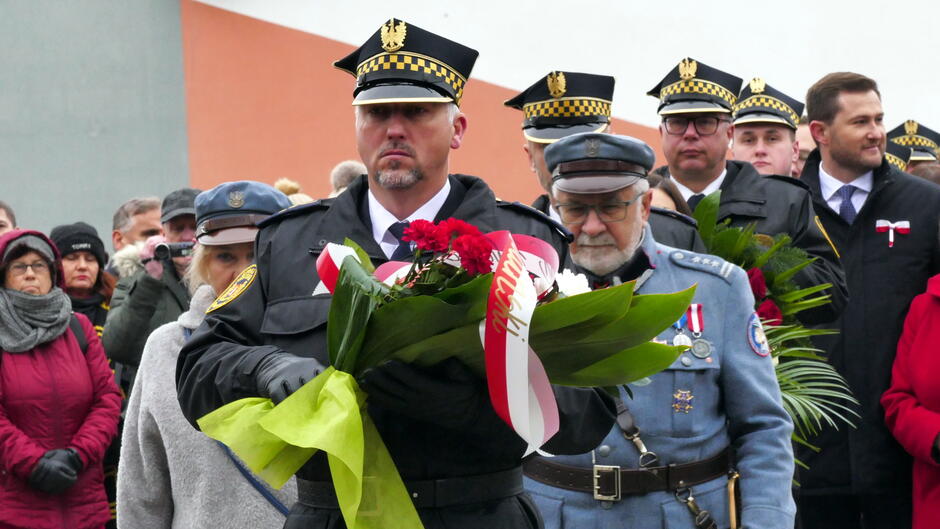 strażnik z wieńcem, za nim uczestnicy i kolejni straznicy