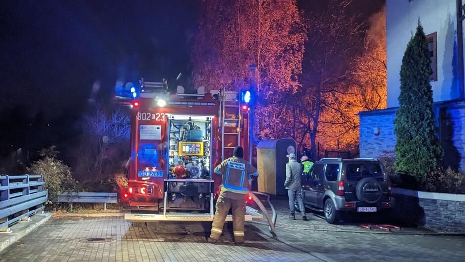 strażacy przy wozie gaśniczym zaparkowany samochód łuna pożaru parking 