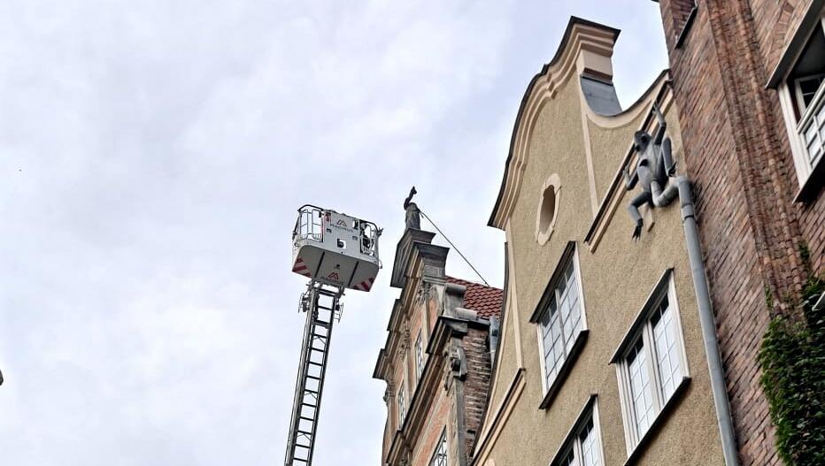 strażacy w koszu na wysokości dachu kamienicy