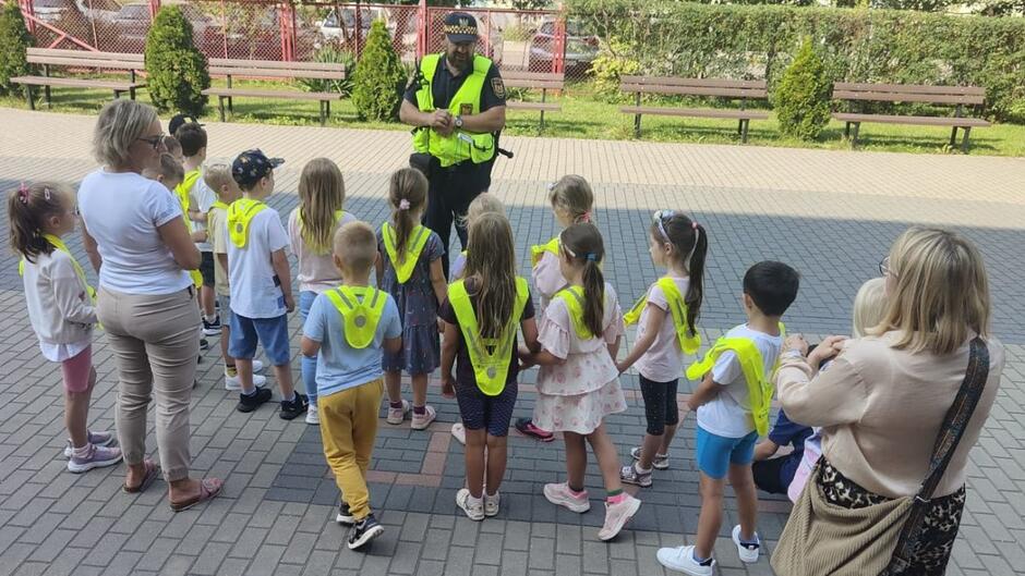 Strażnik miejski uczy dzieci jak przechodzić przez ulicę.