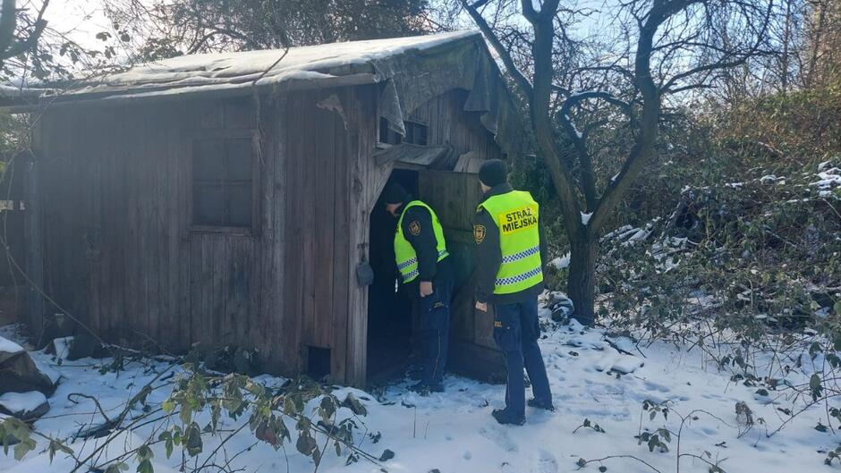 Strażnicy miejscy wchodzą do szałasu w poszukiwaniu osób bezdomnych. 