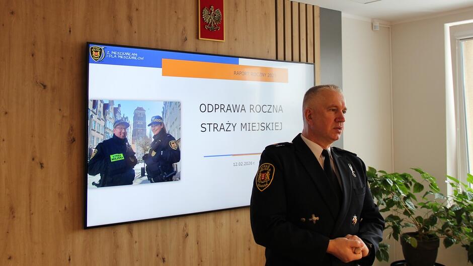 Komendant Leszek Walczak na tle prezentacji.