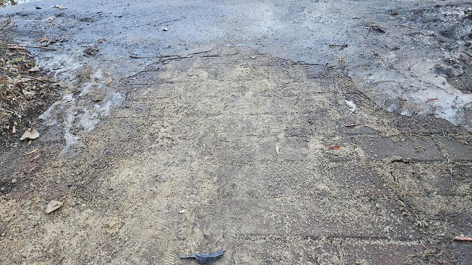 Fragment chodnika pokryty piaskiem i lodem. 