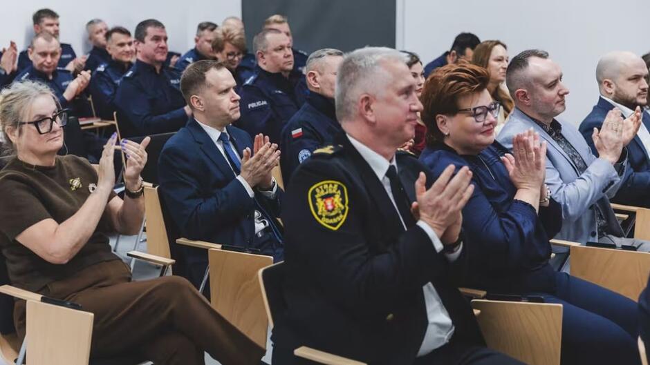 Publiczność zgromadzona podczas odprawy rocznej policji w Gdańsku bije brawo. Na pierszym planie Komendant Straży Miejskiej w Gdańsku Leszek Walczak. 