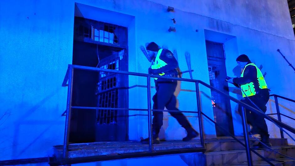 Dwóch strażników miejskich wchodzi do pustostanu, w którym mogą przebywać osoby w kryzysie bezdomności. 