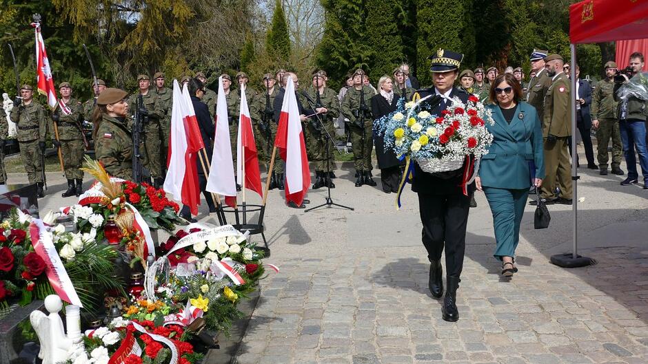 Strażniczka miejska niesie kosz z kwiatami, za nią konsul Ukrainy.