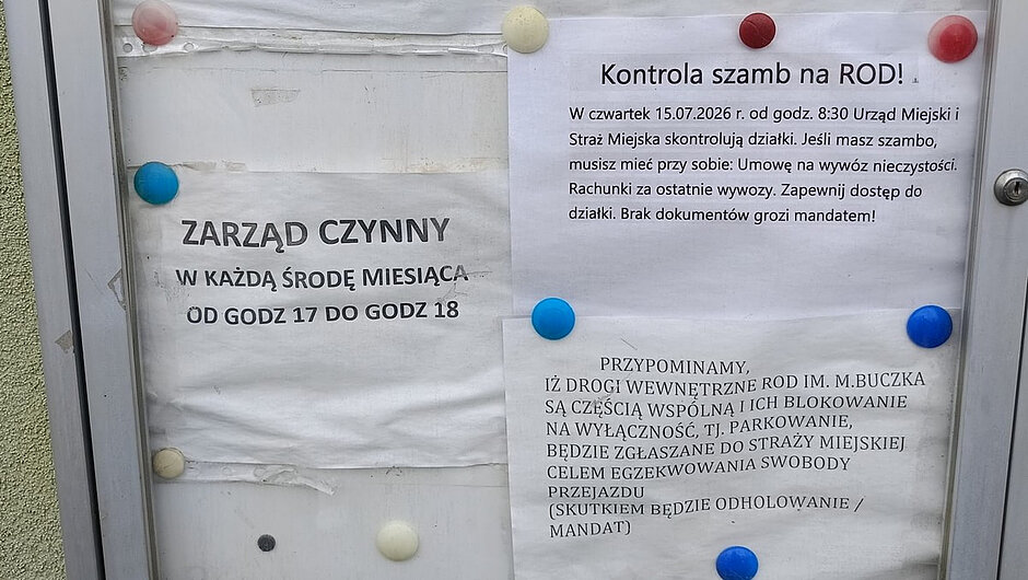 Na zdjęciu widoczna jest przeszklona gablotka informacyjna zamontowana na zewnętrznej ścianie budynku o jasnoniebiesko-zielonej elewacji. W gablocie umieszczono kilka kartek z ogłoszeniami przypiętymi kolorowymi pinezkami.
Najważniejsze informacje zawarte na ogłoszeniach dotyczą Rodzinnego Ogrodu Działkowego im. Mariana Buczka w Gdańsku. Widoczne są:
numery telefonów gospodarzy poszczególnych rejonów ogrodu,
dane kontaktowe do zarządu ROD,
informacja o godzinach pracy zarządu („Zarząd czynny w każdą środę miesiąca od godz. 17 do godz. 18”),
komunikat o kontroli szamb na terenie ROD,
przypomnienie o zakazie blokowania dróg wewnętrznych poprzez parkowanie pojazdów.
Gablotka jest wykonana z aluminiowej ramy i zamykana na klucz. Kartki noszą ślady długotrwałej ekspozycji na warunki atmosferyczne – są lekko pofałdowane i przybrudzone.