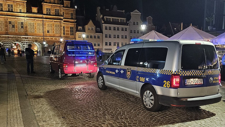 Pojazd Straży Miejskiej podczas czynności służbowych związanych z kontrolą pojazdu na terenie Rynku Starego Miasta w godzinach nocnych.