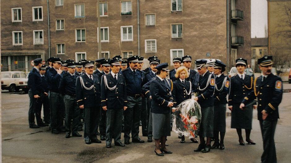 Zdjęcie z lat 90. ubiegłego wieku. Na nim grupa strażniczek i strażników w mundurach galowych na ulicy Gdańska.