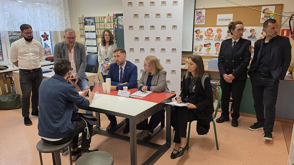 Jeden z mieszkańców przedstawia swoją sprawę podczas indywidualnej rozmowy z przedstawicielami miasta i instytucji miejskich. Spotkanie odbywa się w sali szkolnej przygotowanej na konsultacje z mieszkańcami.
