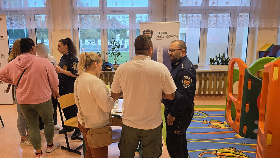 Funkcjonariusze Straży Miejskiej prowadzą konsultacje z mieszkańcami przy stanowisku Referatu Dzielnicowego VI. Uczestnicy spotkania mogą uzyskać informacje, zgłosić problemy oraz zapoznać się z materiałami dotyczącymi bezpieczeństwa w dzielnicy.