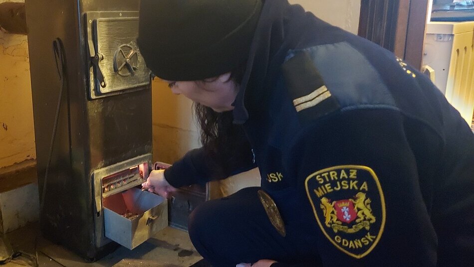 piec typu koza obok strażniczka sprawdzająca popielnik
